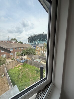 Blick durch ein Fenster auf ein Wohngebiet, im Hintergrund ein großes Stadion.
