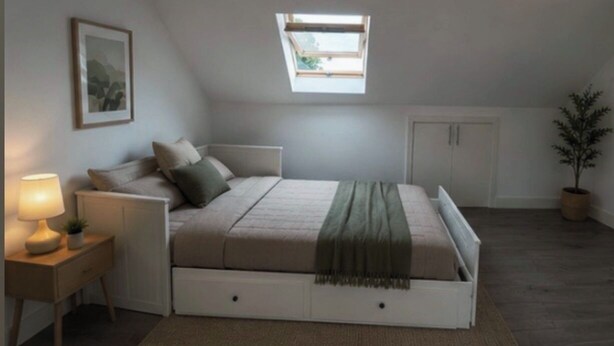 A bedroom with a bed, bedside table, lamp, and a skylight. - 2 Min Walk to Tottenham Hotspur Stadium | Bright Studio (London)