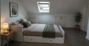 A bedroom with a bed, bedside table, lamp, and a skylight. - 2 Min Walk to Tottenham Hotspur Stadium | Bright Studio (London)