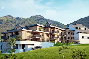 A multi-story building with balconies, a stone base, and a car on a driveway. - Modern studio near ski resort (Ladis)