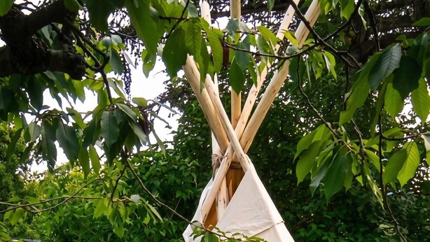 Uma tenda tipi com uma pequena mesa e lanternas do lado de fora.