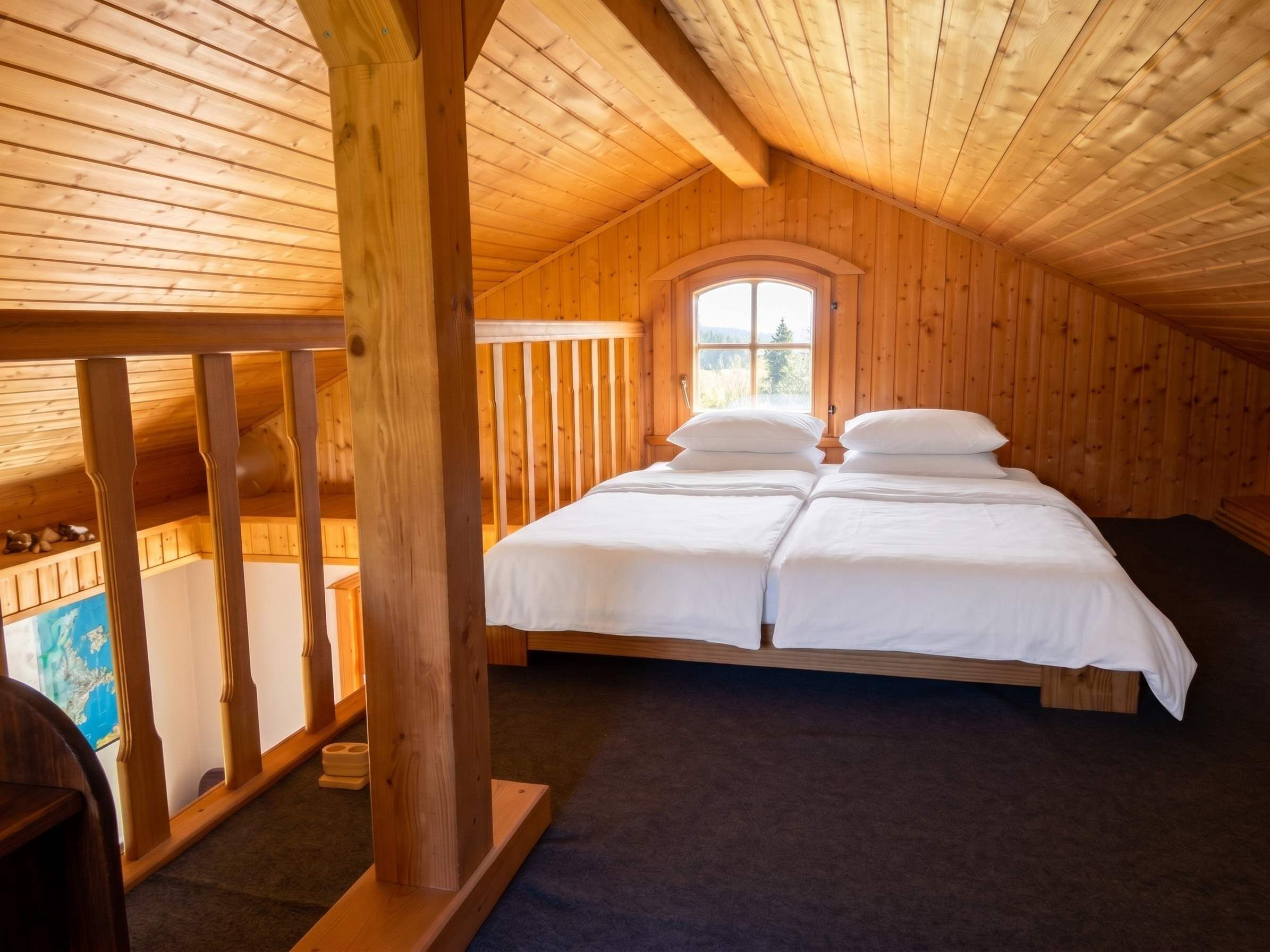 Ein Schlafzimmer einer Holzhütte mit einem Hochbett, einem Fenster mit Blick und einem Holgeländer.