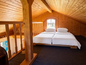 Ein Schlafzimmer einer Holzhütte mit einem Hochbett, einem Fenster mit Blick und einem Holgeländer.