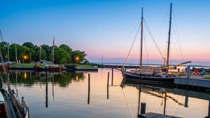 Um calmo areal marítimo com barcos atracados, um cais de madeira e um céu claro.