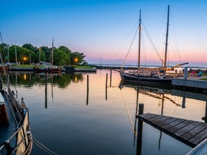 Eine ruhige Marina mit vertäuten Booten, ein Holzsteg und ein klarer Himmel.