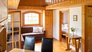 Um interior de madeira com um quarto em mezzanine, um sofá, uma mesa de jantar e vista para o exterior.
