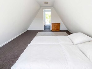 Un dormitorio con cama, un armario de madera y vistas al exterior a través de una puerta.