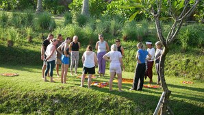 A group of people standing outdoors in a grassy area with trees and plants around. - Desa Cabins (Tabanan)