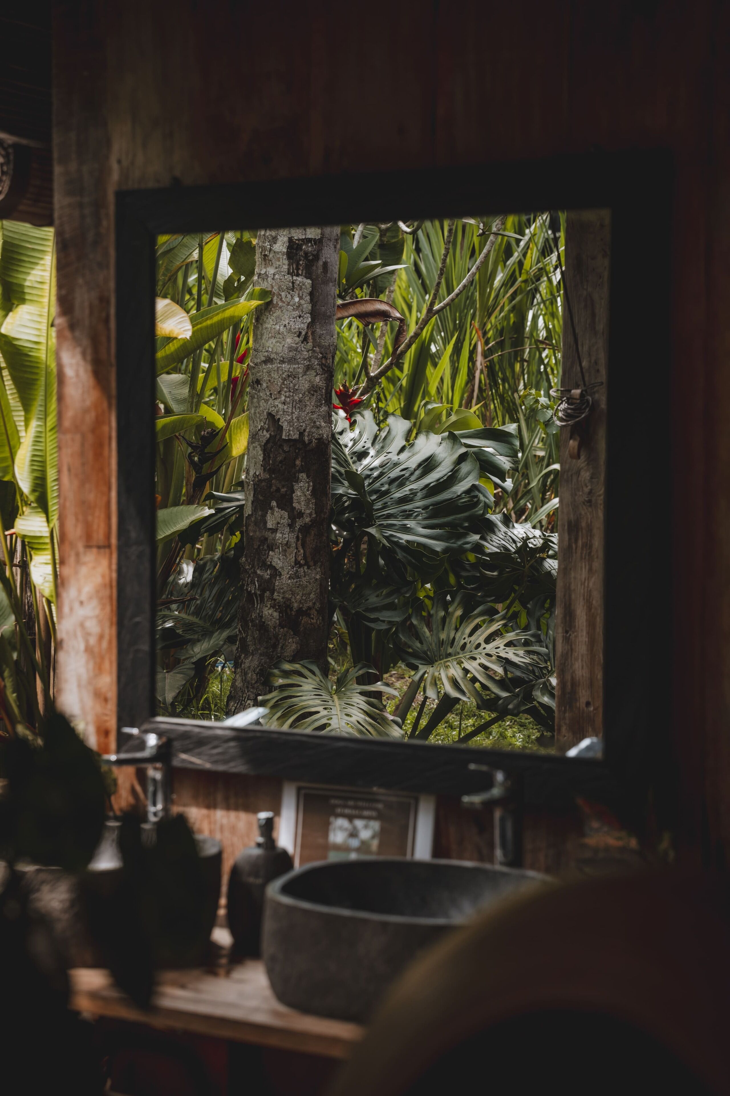 A television displaying a tropical scene, with a wooden frame and a rustic shelf below.