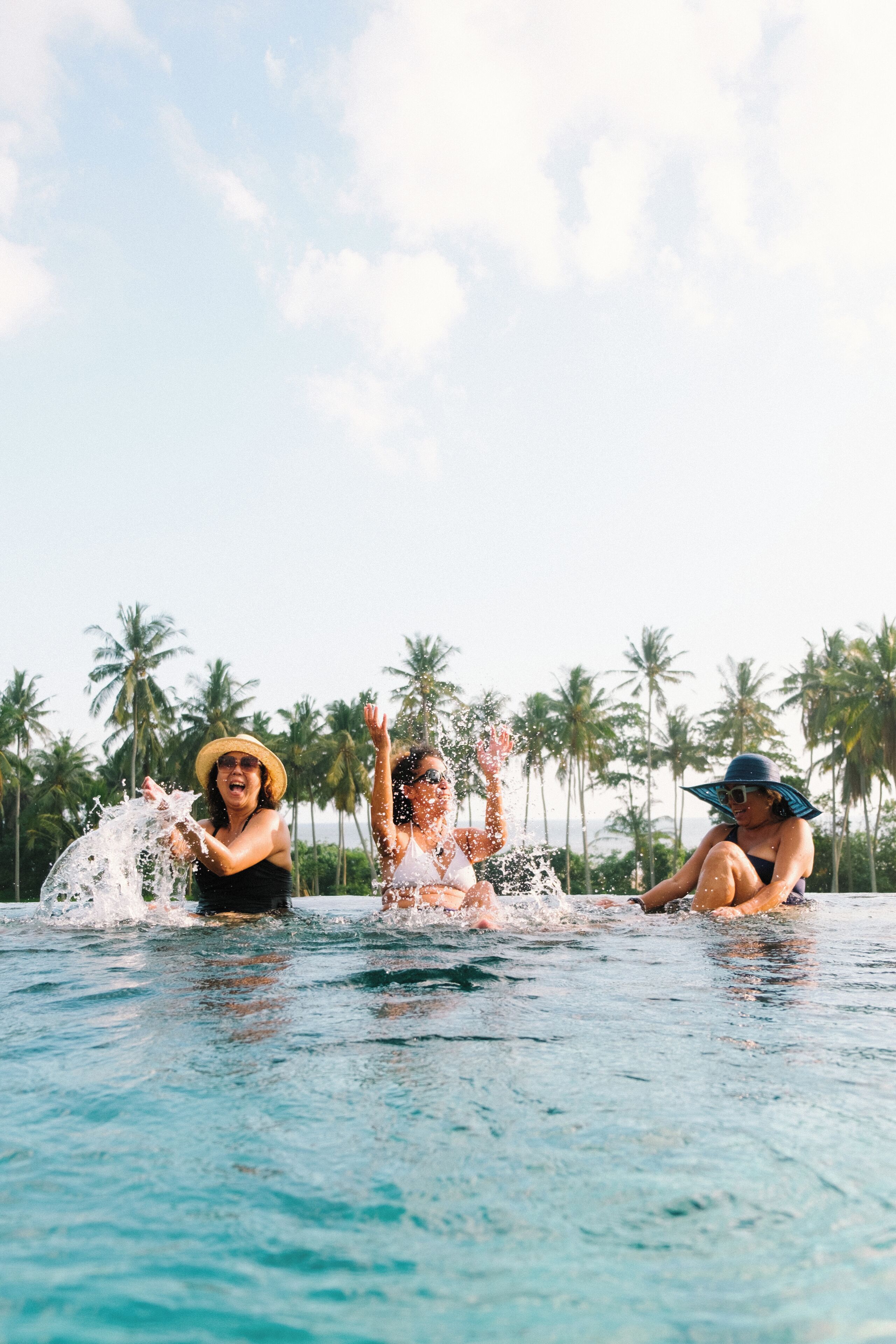 A swimming pool with clear water, surrounded by palm trees.