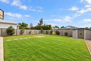 A backyard with a well-maintained lawn, a wooden fence, and a shed. - The Grampian by Ready Set Stay (Cowes)