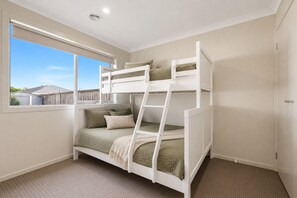 A bunk bed with a ladder, a window with a view of a house, and a carpeted floor. - The Grampian by Ready Set Stay (Cowes)