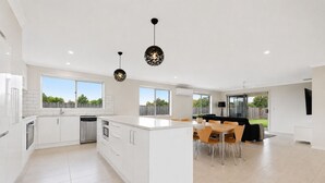 Une cuisine moderne avec des meubles blancs, un îlot central et des luminaires suspendus.