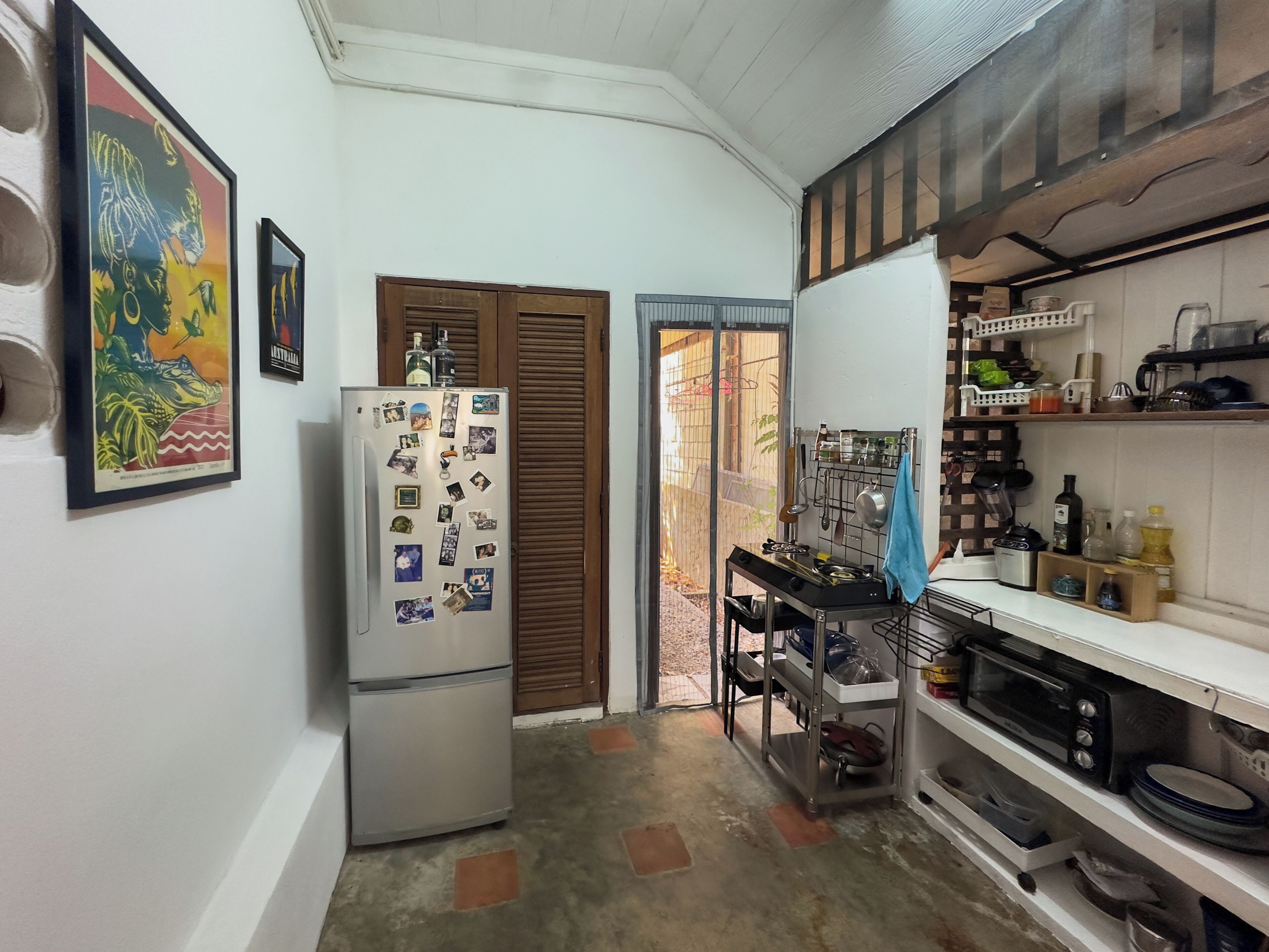 A compact kitchen with a refrigerator, a stove, and a microwave. There are wooden cabinets and a small countertop.