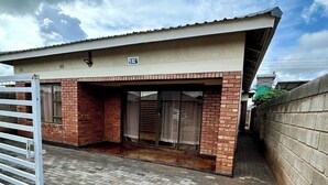 A building with a brick facade, a gated entrance, and a paved courtyard.