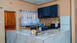 A kitchen with a marble countertop, a built-in oven, and a refrigerator.