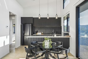 A modern kitchen with a central island, black cabinetry, and pendant lighting.