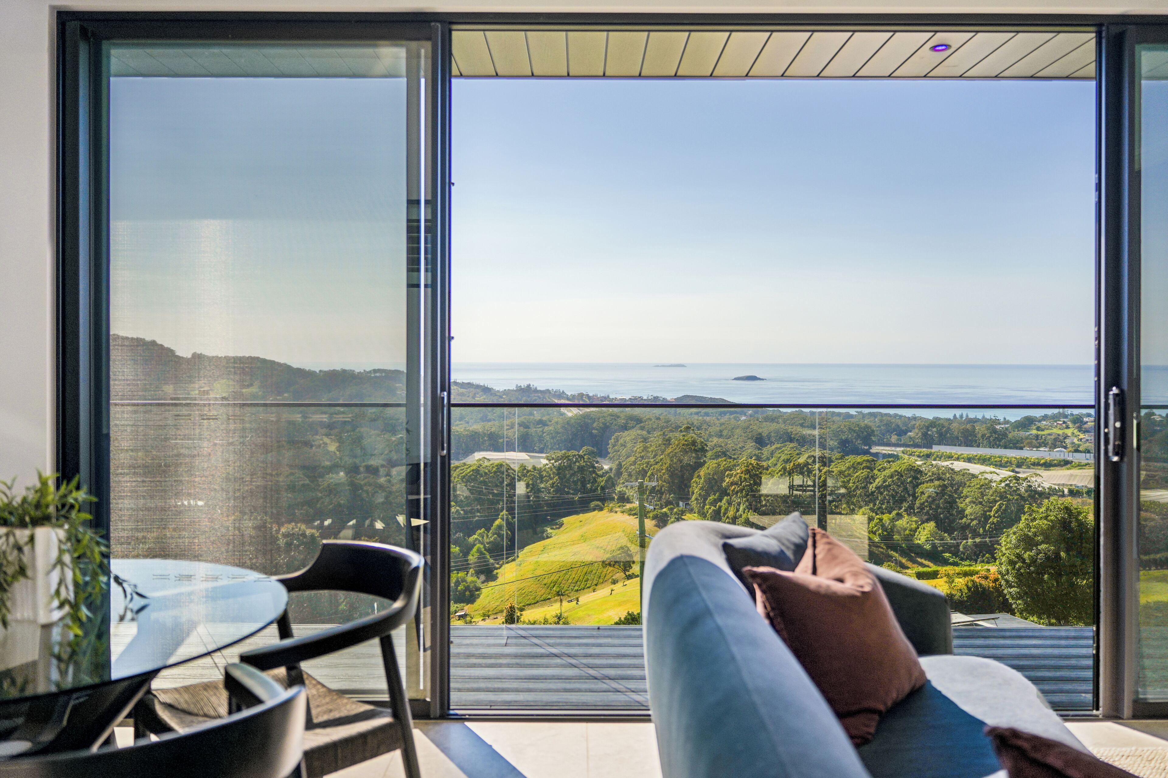 Una habitación moderna con puerta de cristal que da a un balcón con vistas al paisaje costero.