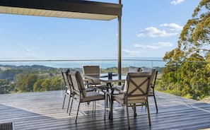 A terrace with a glass balustrade, outdoor seating, and a view of the landscape.