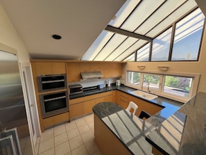 A modern kitchen with a skylight, stainless steel appliances, and a large island.
