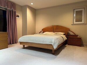 A bedroom with a wooden bed, a nightstand, a dresser, and a window with blinds. - Vancouver West Hillside Villa  4BR Panoramic Views (Vancouver)