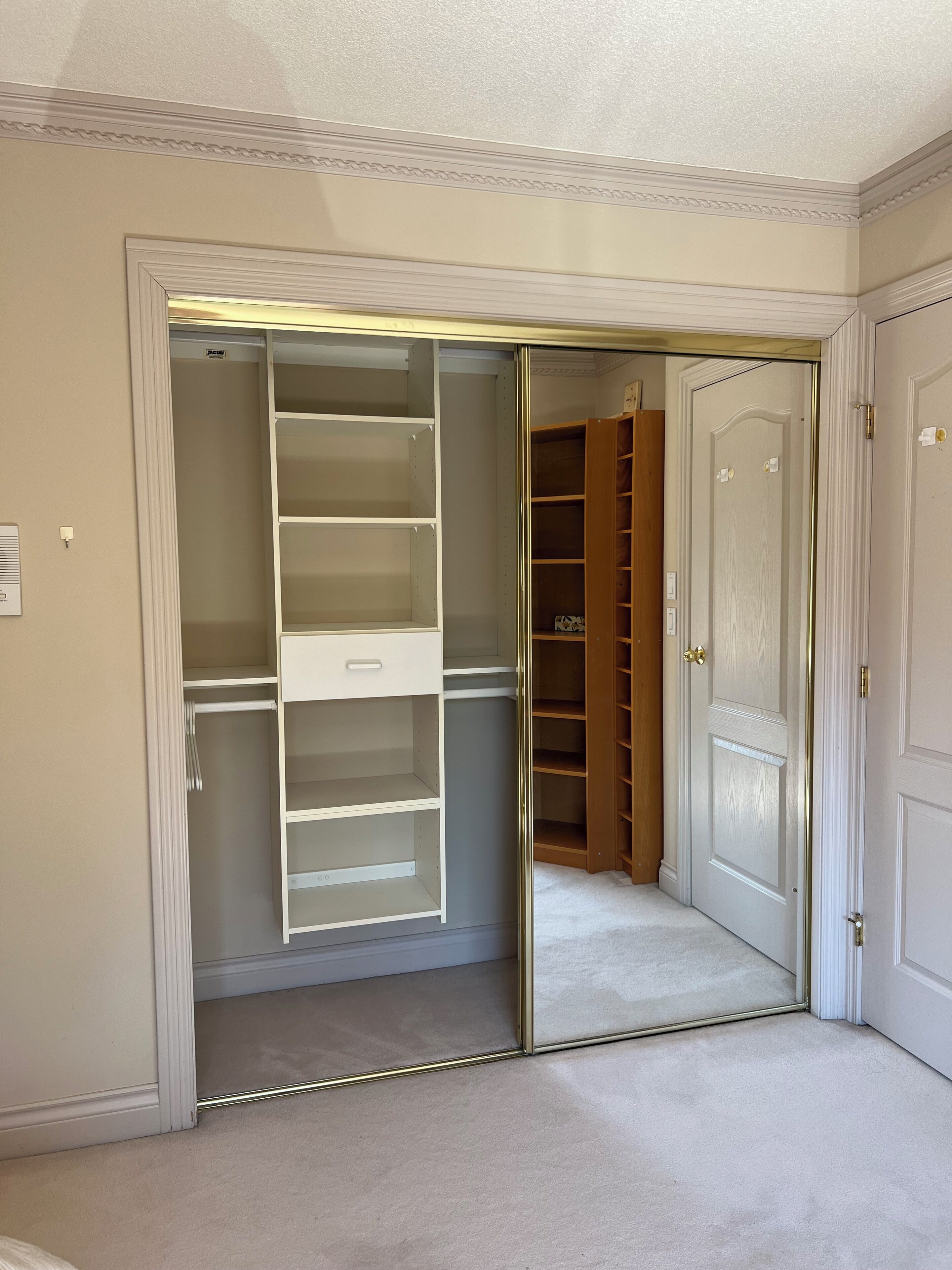 A walk-in closet with open doors, revealing shelves and a hanging rod.