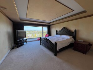 Een hotelkamer met een groot bed, een televisie en uitzicht op de stadsgezichten door het raam.