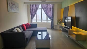 A modern living room with a sectional sofa, a glass coffee table, a flat-screen TV, and a decorative vase.