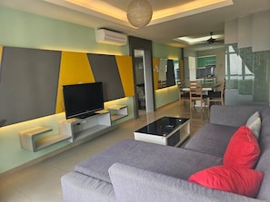 A modern living room with a flat-screen TV, a sofa, and a coffee table. - Putra Majestik Manage By City Haven (Jalan Ipoh)