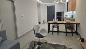 Una sala moderna con sofá, una mesa de comedor con sillas y una zona de cocina con armarios y encimera.