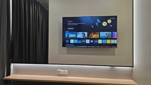 Un televisor de pantalla plana montado en la pared con un estante debajo.