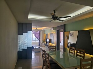 A modern living room with a glass dining table, a ceiling fan, and a TV. - Putra Majestik Manage By City Haven (Jalan Ipoh)