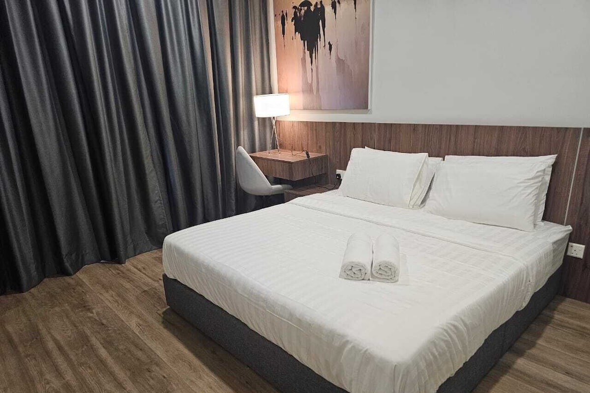 Ein Hotelzimmer mit einem großen Bett, einem Nachttisch mit Lampe und einem Gemälde an der Wand.