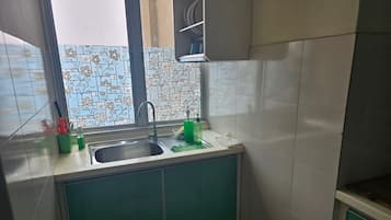 A kitchen with a sink, green cabinets, and a tiled backsplash.