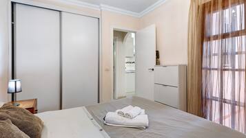 Ein Hotelzimmer mit Bett, Nachttisch, Lampe, Kleiderschrank und Spiegel.