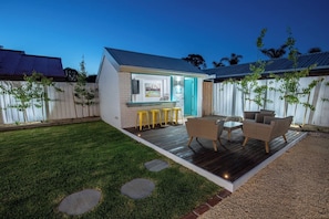 A small house with a deck, outdoor seating, and a TV mounted on the wall. - Ocean Breeze Retreat (Ocean Grove)