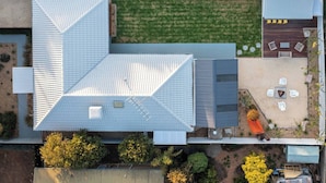 An aerial view of a building with a sloped roof, a patio area with outdoor seating, and a small garden. - Ocean Breeze Retreat (Ocean Grove)