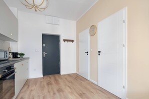 A modern kitchen with a built-in oven, a coffee machine, and a plant on the counter. - Cosy Apartments | Near the Market Square (Poznań)