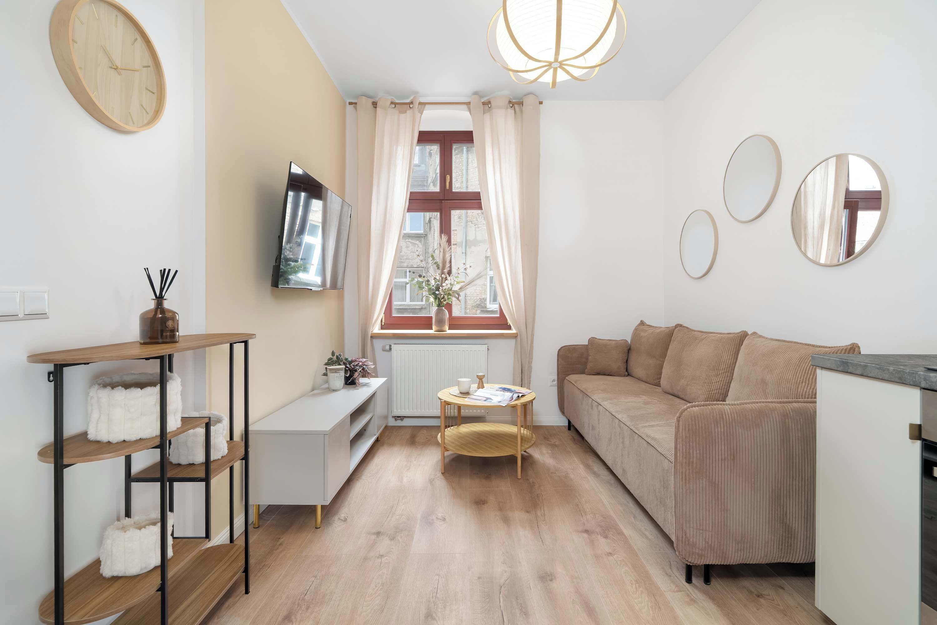 Un salon moderne avec un canapé, une table basse, un téléviseur et une fenêtre avec des rideaux.