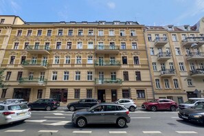 Ein mehrstöckiges Gebäude mit Balkonen, geparkten Autos und blauem Himmel.