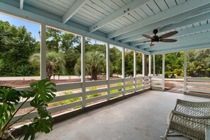 A covered outdoor area with a ceiling fan, white railings, and a concrete floor. - Turtle Egg Coastal Retreat (Pawleys Island)