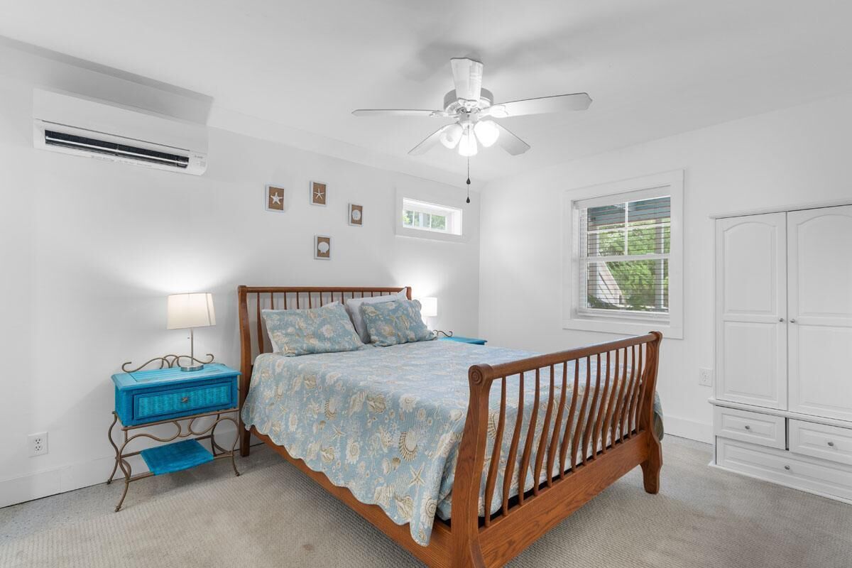 A bedroom with a wooden bed, a ceiling fan, a window, and a wardrobe.