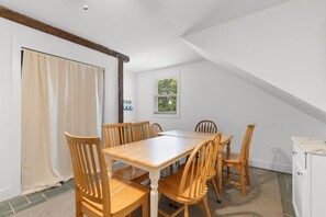 A dining area with a wooden table and chairs, a window with a view, and a white cabinet. - Turtle Nest Coastal Escape (Pawleys Island)