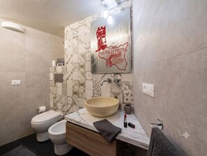 A bathroom with a large bowl sink, two toilets, and a mirror with a decorative wall. - "Casa Mura di Pietra" Townhouse, Modica's Historic Center (Modica)