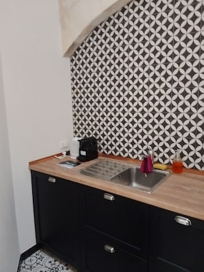 A kitchen with a patterned backsplash, a sink, and a countertop with various items. - "Casa Mura di Pietra" Townhouse, Modica's Historic Center (Modica)