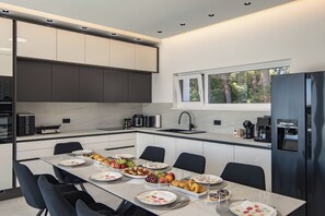 A modern kitchen with a dining area, equipped with appliances and a view of the outdoors. - Villa Peliceti With Grand Pool (Marcana)