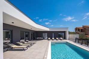 A modern outdoor pool area with lounge chairs and a clear blue sky. - Villa Peliceti With Grand Pool (Marcana)