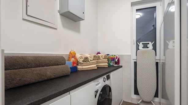 A laundry area with a washing machine, an iron, and towels. - Villa Peliceti With Grand Pool (Marcana)