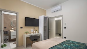 A modern bedroom with a bed, a desk, a chair, a television, and an air conditioning unit. - Villa Peliceti With Grand Pool (Marcana)