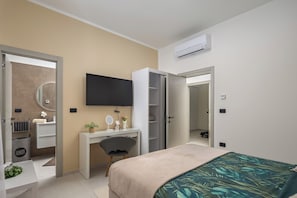 A modern bedroom with a bed, a desk, a chair, a television, and an air conditioning unit. - Villa Peliceti With Grand Pool (Marcana)